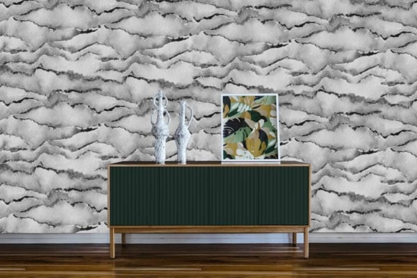 The modern living room features an abstract, black-and-white textured wallpaper. The wallpaper showcases intricate patterns with both sharp and fluid lines in varying shades of black and white. Geometric shapes blend seamlessly with organic forms, creating a dynamic contrast that adds depth to the room. The monochromatic scheme highlights the interplay of light and dark, making it a striking background for the sleek wooden console and its decorative items.