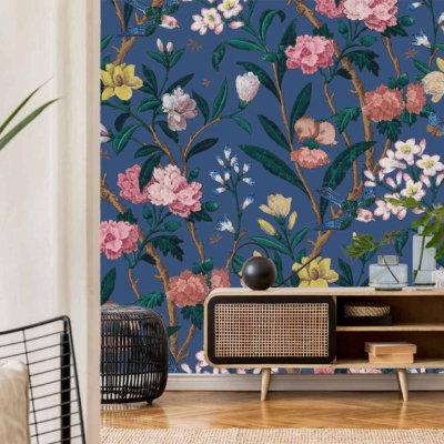 A stylish living room features a dark blue wall with a colorful floral mural. The wallpaper includes vivid reds, soft pinks, lush greens, and touches of gold, creating an eye-catching and vibrant backdrop.
