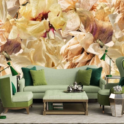 The wallpaper in the modern living room highlights a large floral mural with intricate details. Colors featured prominently in the mural include shades of beige, cream, and light yellow. The floral design showcases delicate petals and leaves, creating an elegant backdrop that complements the green furniture in the space.