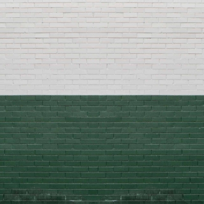 A wallpaper featuring a brick wall with two distinct sections: the upper part is painted white, and the lower part is painted green. The design showcases a symmetrical and clean horizontal divide, creating a striking half-and-half effect. Keywords: brick wall, white upper section, green lower section, symmetrical, horizontal divide.