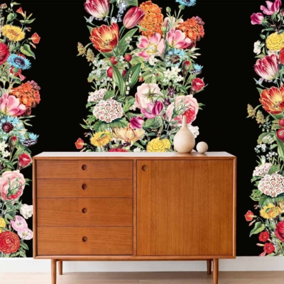 Idas Garden wallpaper features a bold, vibrant floral pattern on a black background. The design includes an array of colorful flowers in shades of red, pink, yellow, and green. Influences from nature are evident through intricate details like leaves and stems, contrasting vividly against the dark backdrop.