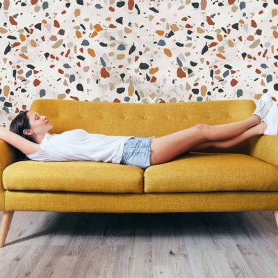 Terrazzo-patterned wallpaper with multicolored specks. The design includes colors like white, blue, pink, and gray that harmonize with the stylish flooring.