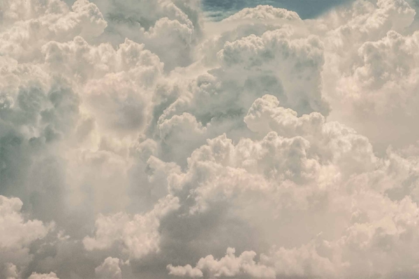 Wallpaper featuring a vast expanse of fluffy white clouds, varying textures and forms creating a dynamic and peaceful atmosphere. Soft, dense clouds dominate with slight hints of blue sky, suggesting a bright day.