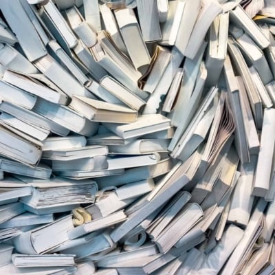 Wallpaper features a large, chaotic pile of books primarily with white covers and pages, arranged in a swirling pattern. Some books are open, others are closed. The scene conveys disarray and abundant knowledge through the dominance of white tones mixed with subtle hints of text and illustrations on pages.