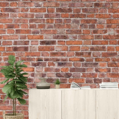The wallpaper features a rustic design with exposed bricks in various shades of earthy red, brown, and occasional hints of white. The texture mimics the rough and aged look of real brickwork, enhancing the room’s minimalist aesthetic.