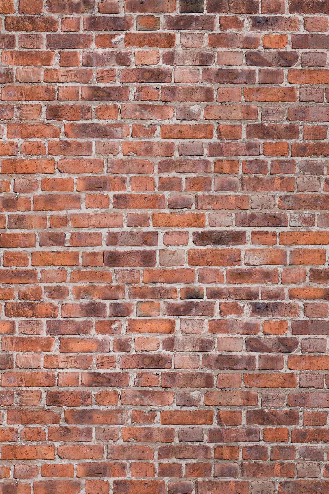 The wallpaper showcases a close-up view of a red brick wall, highlighting bricks with wear and discoloration. It features horizontal brick arrangement with visible mortar joints. Elements include varying shades of red, brown, and gray in the bricks, along with off-white to light-gray mortar lines. The texture appears rugged, emphasizing the essence of building brick by brick.