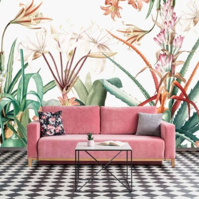 The wallpaper in the Chelsea living room features a vibrant floral mural with large, colorful flowers and lush green leaves. The flowers display a variety of rich hues, including reds, pinks, yellows, and blues. The green leaves add depth and natural contrast against the bright blossoms. This striking mural serves as an eye-catching backdrop to the space.