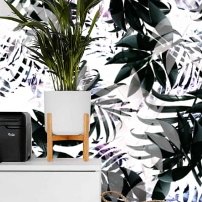 The wallpaper showcases vibrant tropical leaf patterns with shades of green, black, and white. It features intricate designs of various leaves creating a lush and dynamic background.