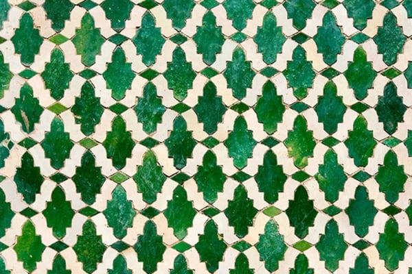 A detailed wallpaper pattern featuring interlocking green and beige geometric tiles, reminiscent of Cyprus. The design is symmetrically repeated, creating a textured and intricate appearance. The green tiles have a slightly glossy finish, while the beige tiles are matte. This wallpaper showcases elements of symmetry, texture, gloss vs. matte contrast, and uses the colors green and beige prominently.