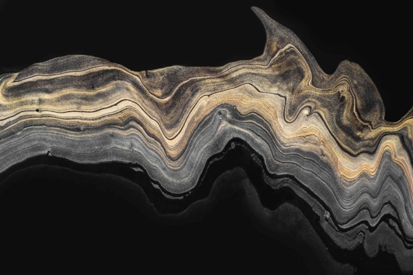Abstract image featuring a wavy, layered pattern reminiscent of geological rock strata. The color palette includes black, gold, and sandy brown. Sweeping lines evoke the energy of natural forces shaping vast fields against a dark background. The wallpaper highlights elements of nature-inspired textures and dynamic movement with earthy tones in an intricate design.