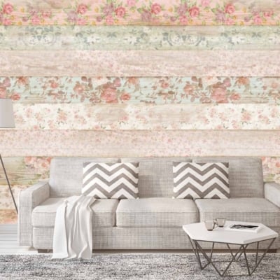 The wallpaper features a colorful, floral-patterned wooden plank design. It includes vibrant hues like pink, yellow, turquoise, and green, intermingled with delicate flower motifs. This eclectic arrangement exudes a coastal charm reminiscent of the English Channel's whimsical decor. The planks are arranged vertically with visible grain textures contributing to the rustic yet lively ambiance of the room.