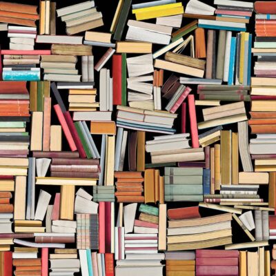 Discover a vibrant, disordered collage of books on the wallpaper. The scene features books of diverse sizes and hues—rich reds, serene blues, vivid yellows, deep greens, and soft pastels. These books are stacked and scattered every which way: horizontally, vertically, and diagonally. The jumbled arrangement showcases an overwhelming yet intriguing abundance of knowledge in every corner.