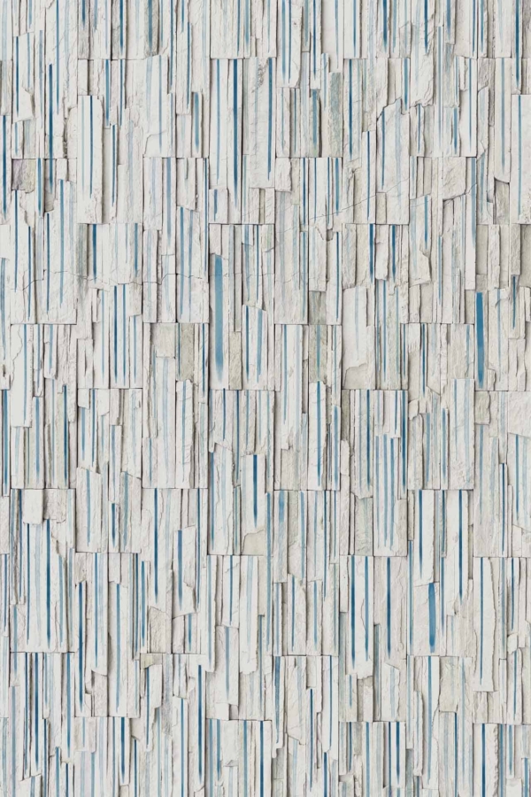 Textured wall with irregularly shaped and sized stone tiles in white and light blue. Tiles are arranged both vertically and horizontally in a random pattern. Dynamic, abstract overlay design with alternating orientations of tiles for added intricacy.