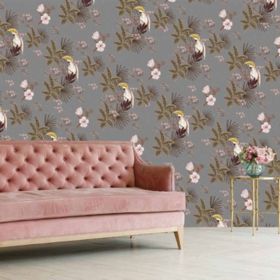 A wall covered in grey floral and tropical bird patterned wallpaper, featuring detailed illustrations of exotic birds in vibrant shades of red, blue, and yellow amidst lush foliage and ornate blossoms in soft hues like peach and cream.