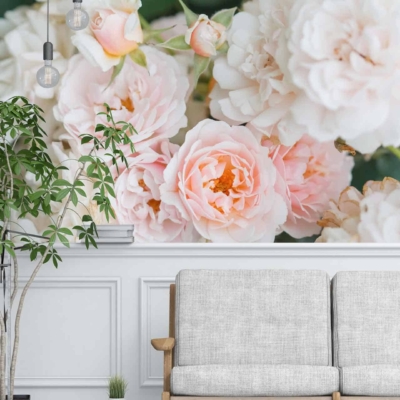 The wall mural features blooming pink and white flowers, reminiscent of a rose garden. The colors are soft, pastel tones creating a relaxing and inviting atmosphere. Elements include large roses and delicate petals.