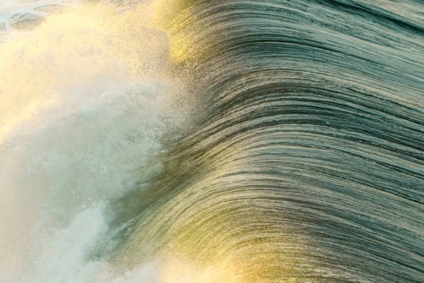 A close-up photograph of a dynamic ocean wave crashing, illuminated by sunlight casting a golden hue on swirling water. The vibrant motion is captured with shimmering blues and iridescent whites, contrasted by warm gold touches—an inspiring reminder to seize the day. This wallpaper includes elements of water movement, sunlight reflection, and ocean energy with hues of blue, white, and gold.