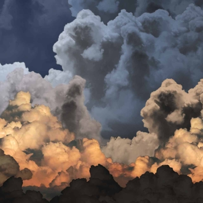 A vibrant, dramatic wallpaper featuring a sky filled with billowing clouds in shades of gray, white, and orange. The clouds are lit by a warm, low-angle light, creating depth and movement. Silver linings add contrast to the stormy yet mesmerizing atmosphere. Perfect for adding drama and warmth to any room.
