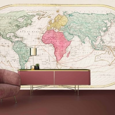 A room with a large vintage world map mural from Simply Mapped on the wall. The mural features soft beiges, muted blues, and pale greens with intricate geographical details and aged textures that provide an antique feel.