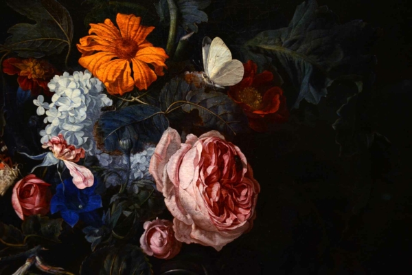 The wallpaper in The Studio's painting features a delicate and intricate floral design. It includes motifs of large pink roses, vibrant orange marigolds, and pristine white hydrangeas, all woven with verdant green leaves. Additionally, there are periodic appearances of small white butterflies scattered throughout the pattern. The overall color palette is rich with hues of pink, orange, white, and green against a softly textured background that complements the vibrant floral elements.