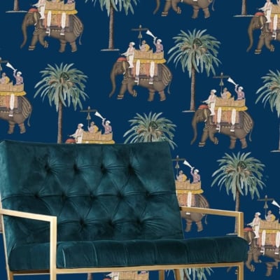 Dark blue wallpaper with a repeating pattern of elephants in procession. Elephants are adorned with riders and palm trees. Colors include rich golds, deep blues, greens, and hints of red. Exotic, vintage design inspired by traditional Indian motifs and grand wedding celebrations.