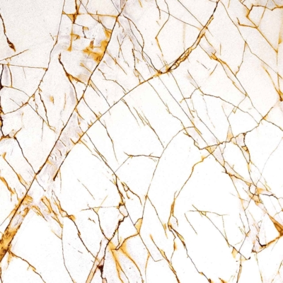Close-up view of a white marble surface with intricate gold and brown veining patterns. The web-like design features intersecting veins forming abstract shapes, adding texture and depth to the smooth, polished stone. Colors include white, gold, and brown.