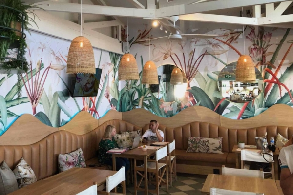 The wallpaper features large, leafy tropical mural designs in lush greens with accents of deep blues and vibrant yellows.