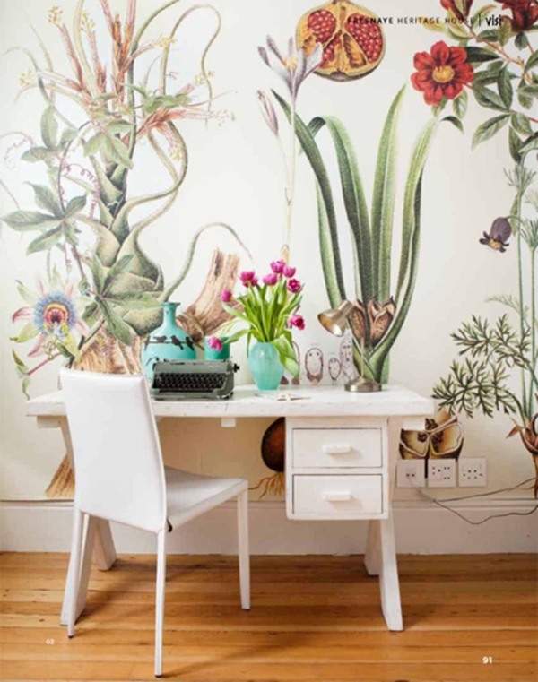 The wallpaper features large botanical illustrations with vibrant greens, earthy browns, and soft floral hues. It showcases intricate leaf patterns and blooming flowers, creating a lush, nature-inspired backdrop ideal for emphasizing natural beauty in any setting.