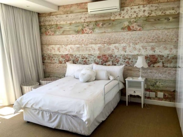 Floral-patterned wooden accent wall features delicate blossoms in shades of blush pink, soft ivory, and muted green leaves against a warm, rustic wood background. The intricate designs add a touch of elegance and nature-inspired charm to the room.