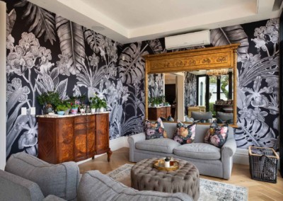 A stylish living room boasts vibrant black and white floral wallpaper. The design is characterized by bold, contrasting flowers and intricate leaf patterns, creating an eye-catching backdrop. The wallpaper features striking shades of black interwoven with crisp white, enhancing the room's sophisticated ambiance. This dynamic design is perfect for adding a touch of elegance to any space.