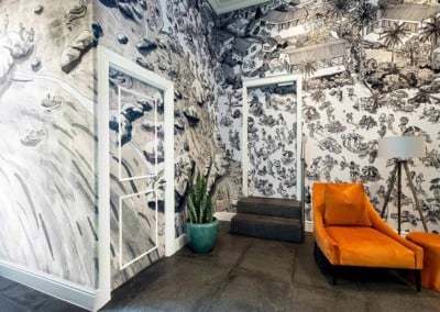 A modern home interior showcases a high-contrast, black-and-white mural on the walls, depicting intricate and detailed scenes.