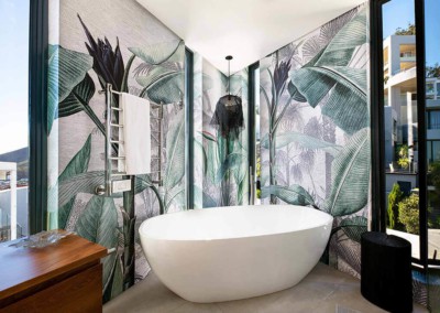 The homepage features a striking tropical leaf wallpaper in rich greens and deep blues, with intricate patterns of lush foliage. This vibrant backdrop adds a lively touch to the modern bathroom, enhancing the serene yet exotic atmosphere.