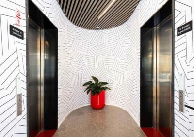 The wallpaper in the elevator lobby features a striking geometric pattern in black and white. The design includes various shapes and angles, creating a dynamic, modern visual impact.