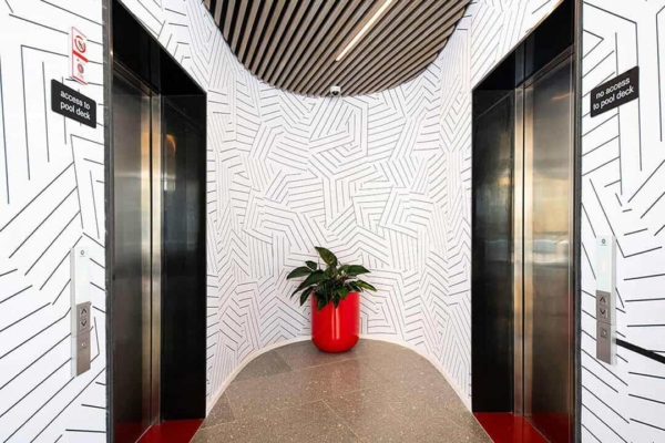The wallpaper in the elevator lobby features a striking geometric pattern in black and white. The design includes various shapes and angles, creating a dynamic, modern visual impact.