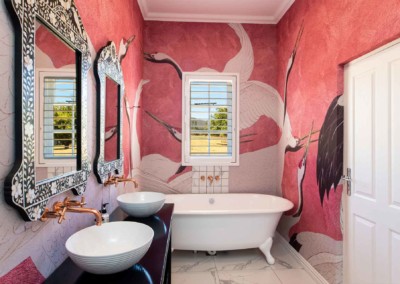 A bathroom with **pink and red wallpaper** featuring **large crane designs**.