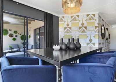 The geometric-patterned accent wall features a dynamic mix of bold shapes and lines in shades of navy, gold, and white. This striking design adds visual interest and sophistication to the dining area.