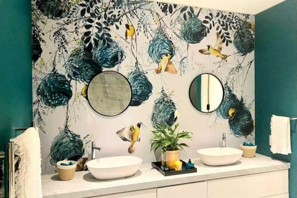 A vibrant mural features birds, nests, and teal elements between two round mirrors.