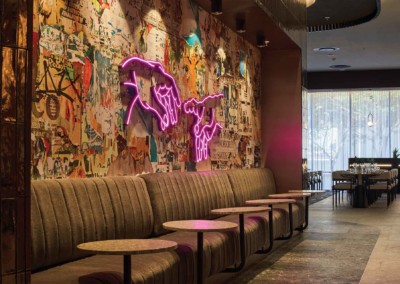 The wallpaper is eclectic graffiti art featuring a mix of vibrant colors like red, blue, yellow, and green with urban-themed motifs. A prominent feature is a pink neon light sculpture shaped like two hands making the "okay" gesture.