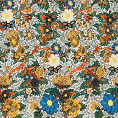 A vibrant and intricate floral wallpaper pattern featuring blue, yellow, orange, and white blossoms interwoven with green foliage. Detailed ornamental designs against a light, textured background highlight Sadie's sophisticated touch. Key elements: colorful flowers, green foliage, detailed designs, light background.
