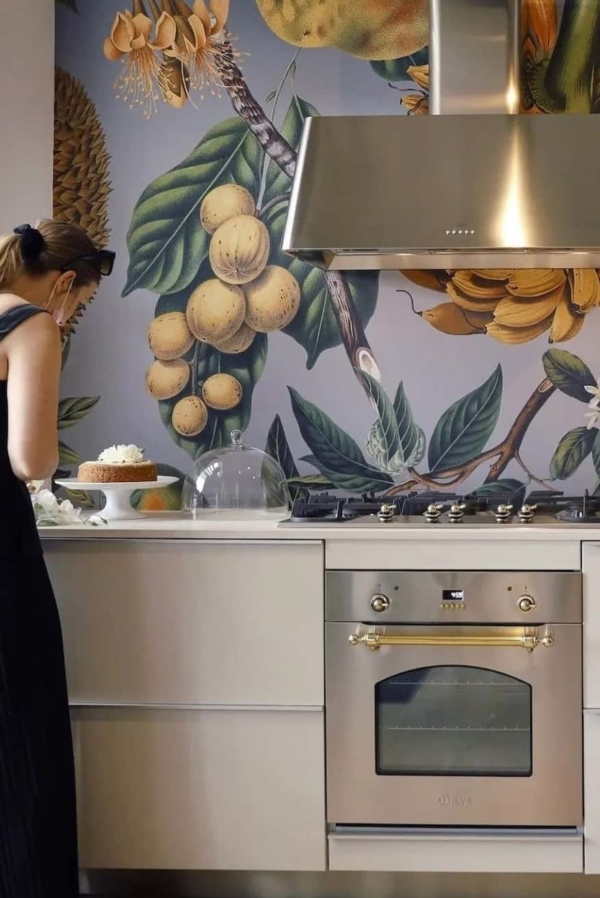 The wallpaper features large botanical illustrations in vibrant colors, including greens, reds, yellows, and blues. The designs are detailed and nature-inspired, with various flowers and leaves creating a lively backdrop.