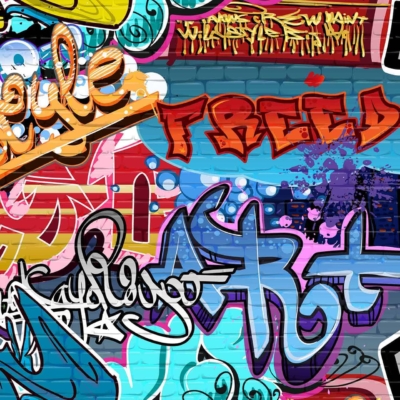 A graffiti mural covers a brick wall with colorful tags and artistic designs. Prominent words like