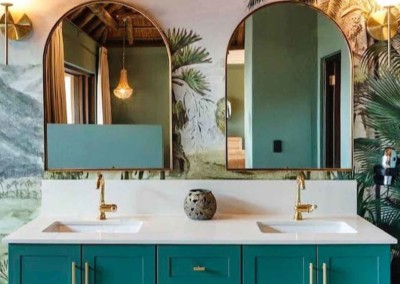 The wallpaper showcases a tropical mural with lush palm trees, offering rich hues of deep green and vibrant emerald. Accents include highlights of lighter greens and splashes of other exotic foliage in varying shades. This botanical theme brings a sense of jungle luxury to the space, perfect for creating a bold statement in any bathroom design.
