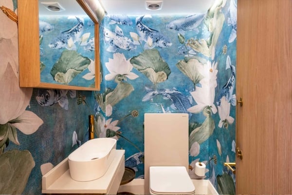 A modern bathroom showcases vibrant, aquatic-themed floral wallpaper. This striking wallpaper features elements like corals, seaweed, and exotic flowers in a mesmerizing palette of blues, teals, and greens. The intricate designs incorporate touches of orange and pink blossoms adding a splash of color that mimics an underwater paradise. Perfect for enhancing any interior design portfolio with a bold and refreshing accent wall.