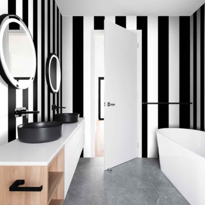 The Right Stripe bathroom features striking black and white vertical striped wallpaper. The bold, alternating black and white stripes create a modern, chic look that defines the space. The contrast of the vivid black and crisp white stripes adds depth and sophistication to the room. This monochromatic pattern draws attention, making it an eye-catching backdrop for other elements in the bathroom while maintaining a sense of simplicity and elegance.