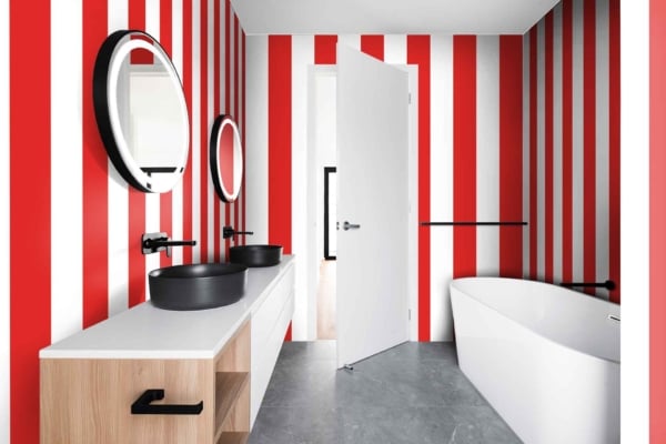 The modern bathroom features "The Right Stripe" wallpaper with bold red and white vertical stripes, creating a striking contrast. This distinctive pattern lays the foundation for the room's contemporary design. The vibrant red stripes paired with crisp white ones add energy and elegance to the space, making it a standout element among the other décor features.