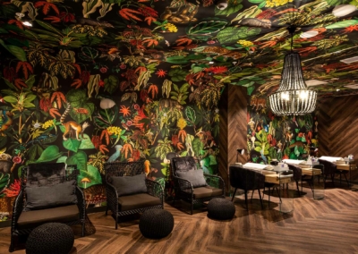 The wallpaper is lush, colorful, and jungle-themed. It features vibrant elements such as green tropical leaves, exotic flowers in red and orange hues, vivid birds with blue feathers, and playful monkeys.