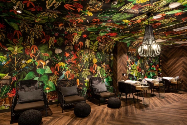 The wallpaper is lush, colorful, and jungle-themed. It features vibrant elements such as green tropical leaves, exotic flowers in red and orange hues, vivid birds with blue feathers, and playful monkeys.