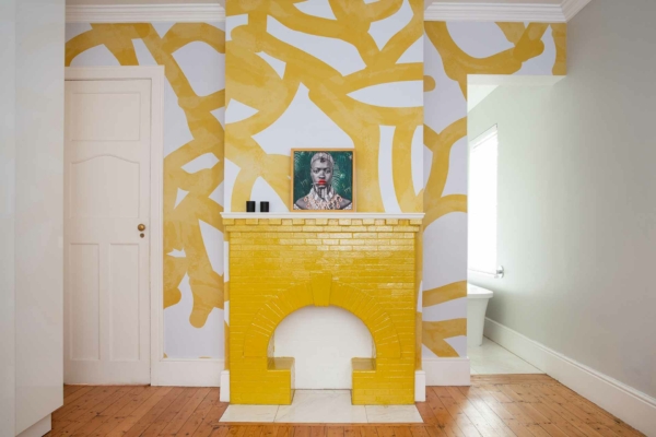 The wallpaper in the modern room features an abstract pattern with yellow and white colors. Elements include intricate designs and geometric shapes, creating a vibrant, visually appealing background.