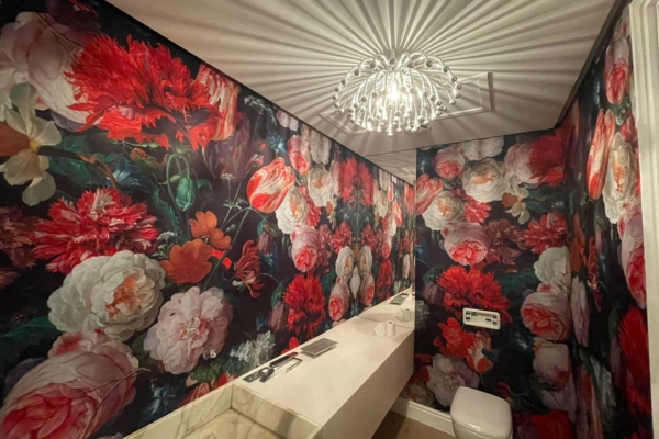 A bathroom featuring vibrant floral wallpaper adorned with large red, white, and pink flowers.
