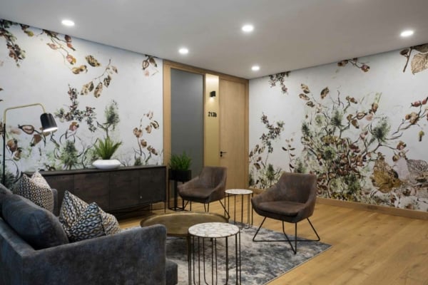 Botanical patterned wallpaper featuring lush green leaves, delicate white flowers, and subtle golden accents.