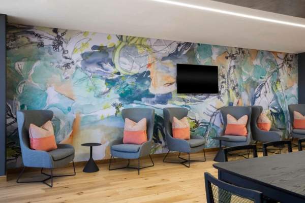 Colorful abstract mural featuring vivid shades of blue, red, yellow, green, and purple. Swirling patterns, geometric shapes, and bold lines create a dynamic visual impact.
